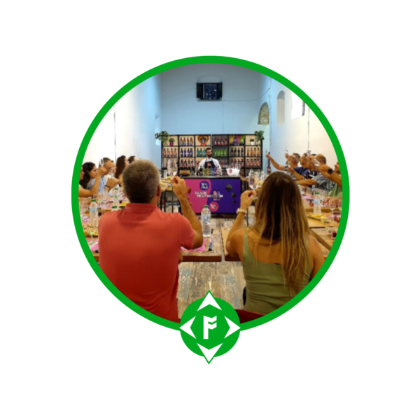 Grupo de personas participando en una cata de ginebra y productos andaluces en un ambiente tradicional, brindando juntos alrededor de una mesa, enmarcado con el logotipo verde de Ansur-TEILFE en la parte inferior